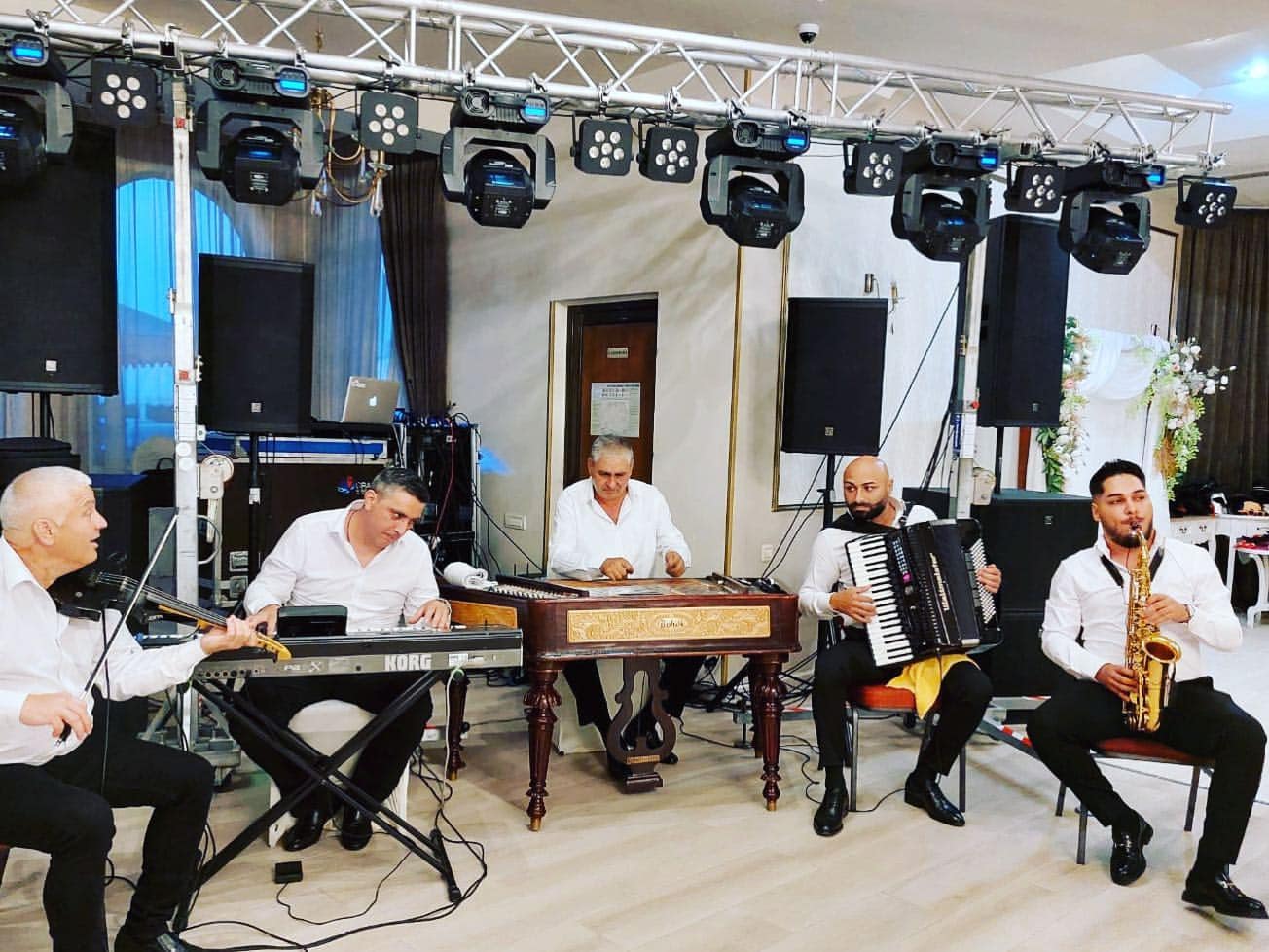 Formația pe scenă: clapă, țambal, acordeon și saxofon, sub luminile sălii