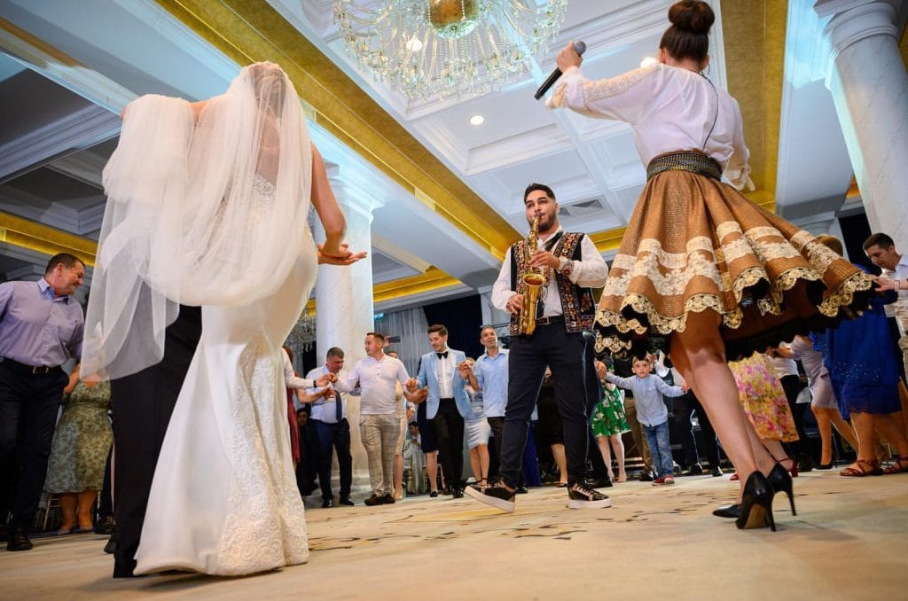 Mireasa cu voalul ridicat în horă, alături de saxofonistul formației