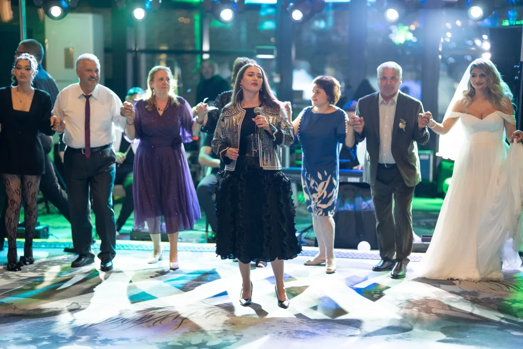 Ioana Balan cântând în mijlocul horei, la o nuntă, cu mireasa și invitații