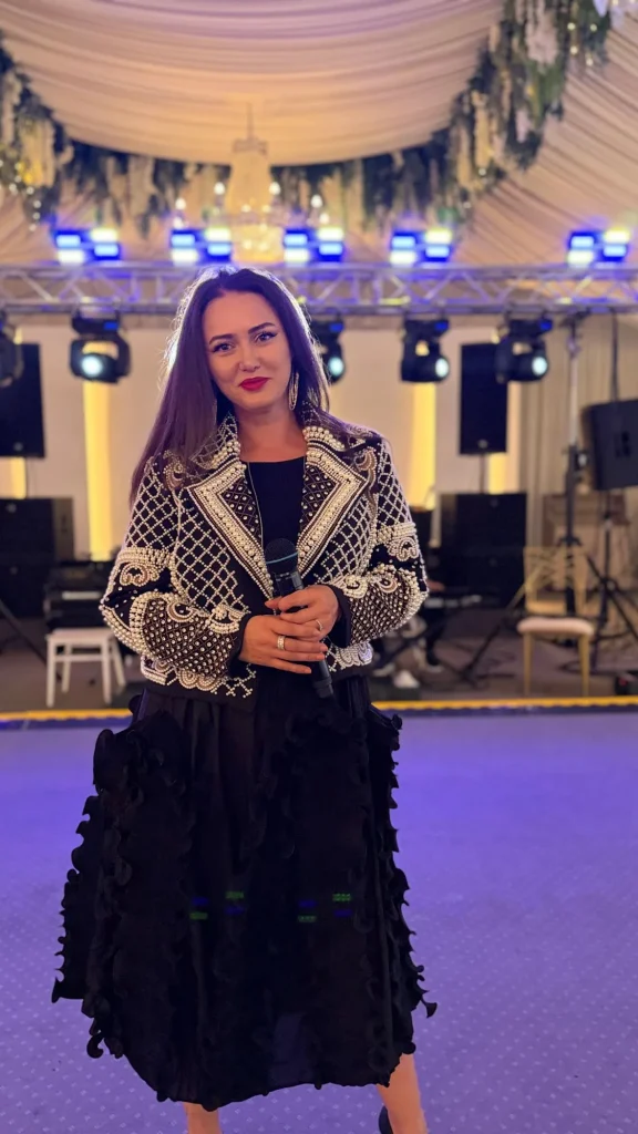 Ioana Balan cu microfonul în mână, în fața scenei cu lumini